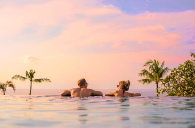 Romantic couple looking at beautiful sunset in luxury infinity pool